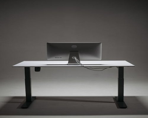 A clean workspace featuring an adjustable chair, proper monitor height, and a glass of water